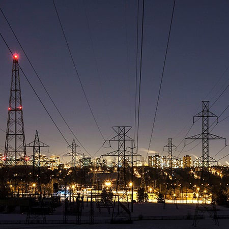 Electricity towers at night with city light up in background