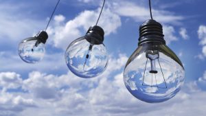 Light bulbs against a blue sky with clouds